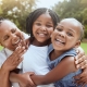 Love, black family hug and grandmother with children enjoy outdoor quality time together, peace or nature park freedom. Fun kids, bond and portrait of excited sisters play with grandma on grass field.